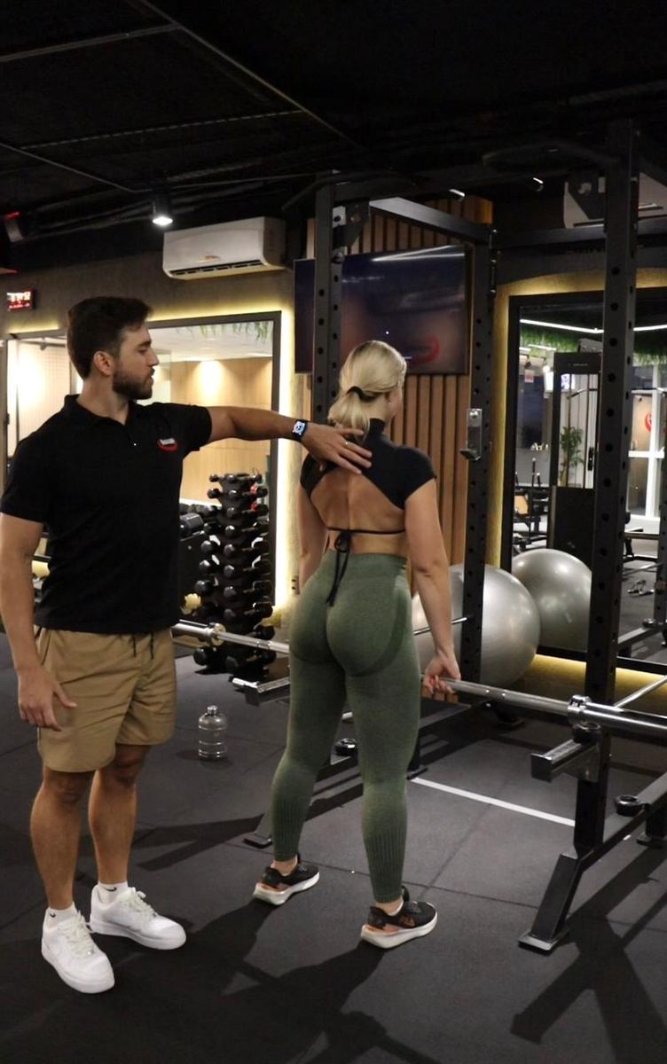 Professor corrigindo a postura de uma aluna antes do exercício